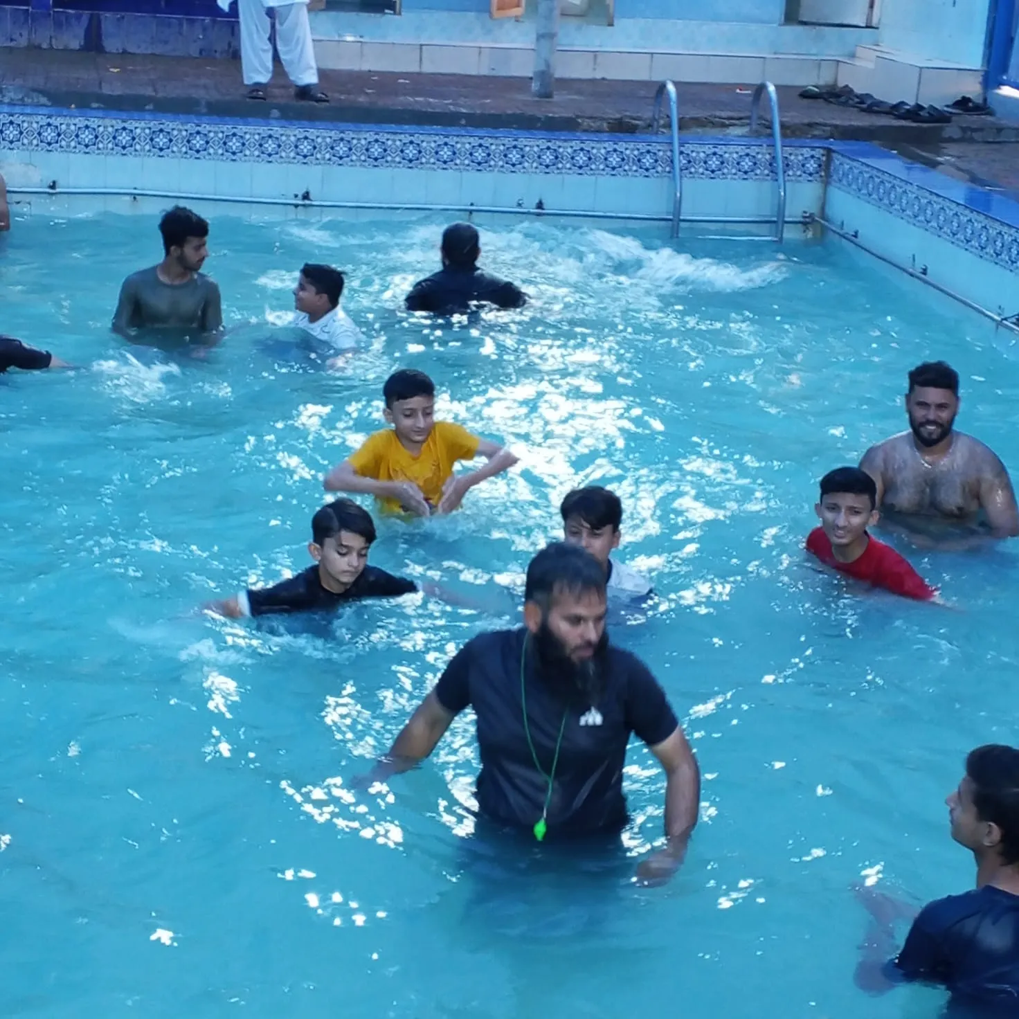 Zeeshan in the pool with children during a swimming lesson.