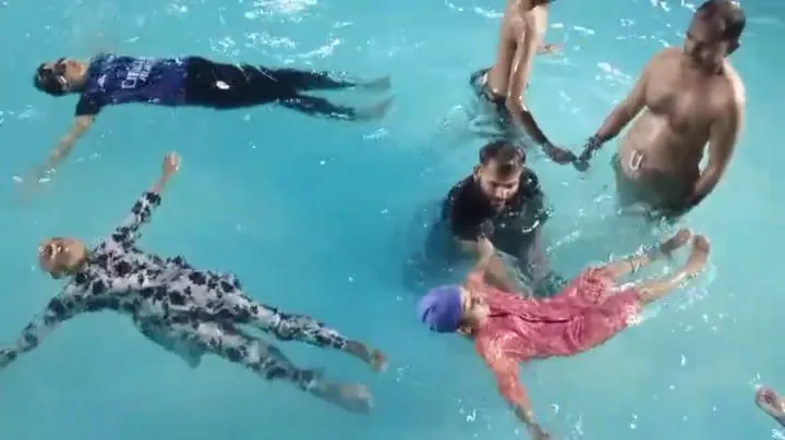 Zeeshan in the pool with young swimming learners.